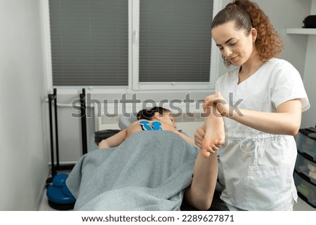 Rehabilitation Specialist, Physical Therapist Makes Foot Massage To Child With Cerebral Palsy, Scoliosis. Health Specialist, Rehabilitation. Horizontal plane. High quality photo