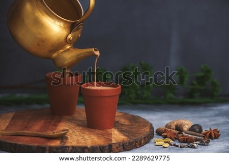 Selective Focused, Herbal tea is under process of Pouring in Earthen cups known as Kulhad. Locally called Kulhad chai or cutting chai or masala chai or matka tea. Mud pot tea cups with bio degradable Royalty-Free Stock Photo #2289629775