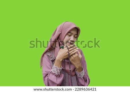 beautiful asian muslim woman hijab holding  prayer beads in her hand with green background. photos of Muslim women wearing hijab with Islamic and Ramadan concepts
