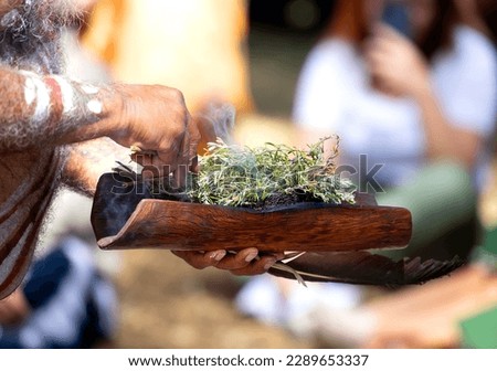 Human hands hold wooden dish with Australian plant branches, the smoke ritual rite at a indigenous community event in Australia Royalty-Free Stock Photo #2289653337