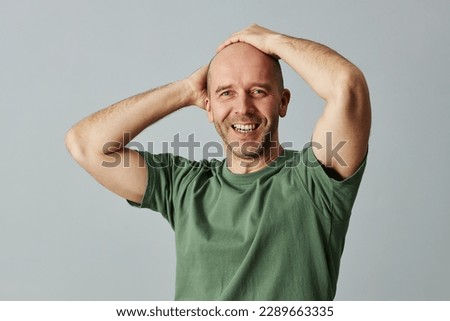 Waist up portrait of confident bald man smiling at camera and posing with hands on head Royalty-Free Stock Photo #2289663335