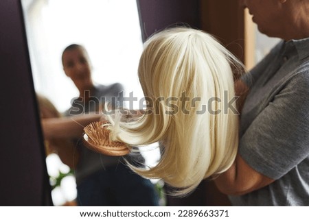 Closeup of unrecognizable woman brushing wig by mirror at home, copy space Royalty-Free Stock Photo #2289663371