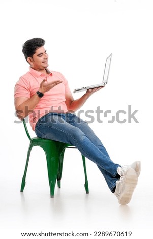 Young indian man pointing of laptop screen on white background.