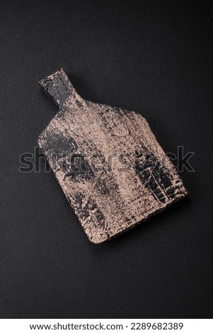 Empty wooden cutting board on dark concrete background. Preparing the kitchen table for cooking at home