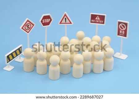 Wooden people figures and prohibition and warning signs around them on blue background.