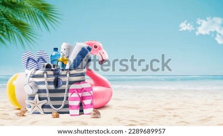Beach bag with accessories and cute inflatable flamingo on a tropical beach, summer vacations and travel concept Royalty-Free Stock Photo #2289689957