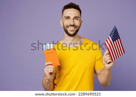 Traveler man wear casual clothes hold passpotr ticket American flag isolated on plain purple background studio. Tourist travel abroad in free spare time rest getaway. Air flight trip journey concept