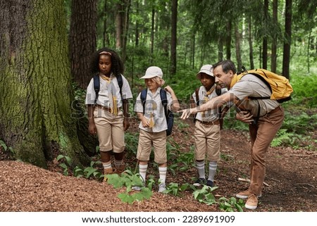 Full length view at diverse group of scouts exploring nature during field trip in forest Royalty-Free Stock Photo #2289691909
