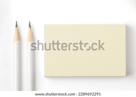 Simple pale yellow blank  business card mock up on a white background with white pencils