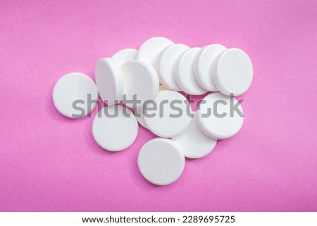 White soluble tablet pills isolated on a pink background. Top view, flat lay.
