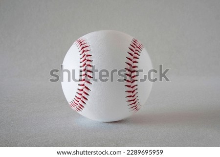 Close-up of a white baseball with red stitching on a grey background