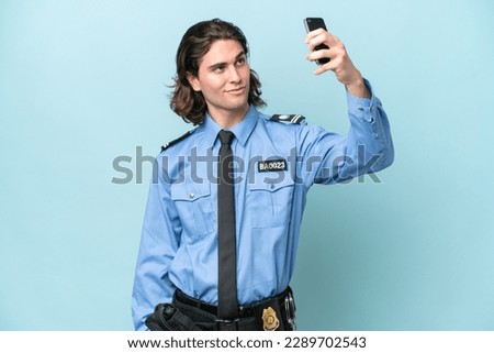 Young police caucasian man isolated on blue background making a selfie