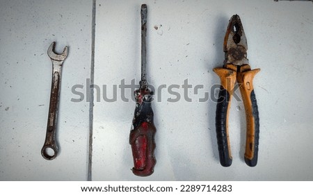 A wrench, screwdriver and pliers. With a white ceramic background. A little light from the right.