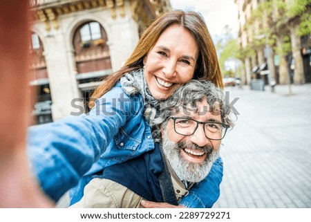 Senior couple taking selfie with smart mobile phone outside - Two aged tourists enjoying together summer vacation - Life style concept with mature female and male smiling at camera