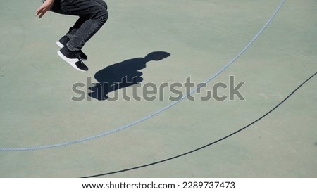 Isolated shadow of a child jumping rope on green ground. Concept of wellness, energy Royalty-Free Stock Photo #2289737473