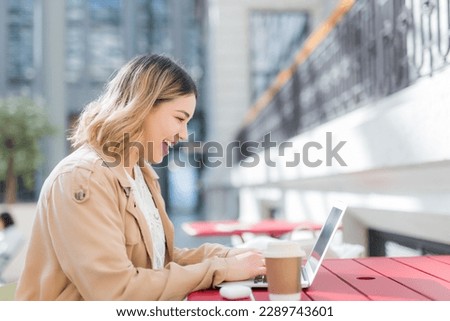 Happy woman using a red laptop in a bar terrace