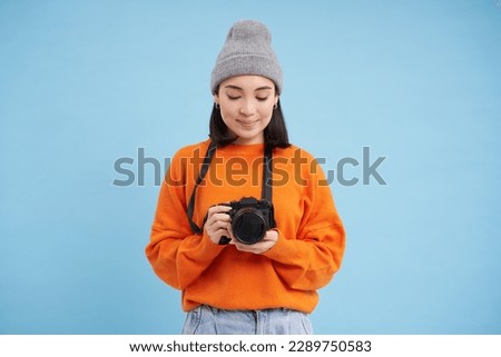 Passionate asian girl photographer, taking pictures on her digital camera, capturing moments outdoors, shooting photos, blue background.