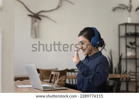 Smiling Indian woman student or businesswoman make video call by business or study sit at desk at home office. Virtual meeting, workflow, learning with tutor using modern tech, video conference event Royalty-Free Stock Photo #2289776115