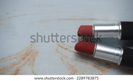 two red lipsticks on a white wooden table
