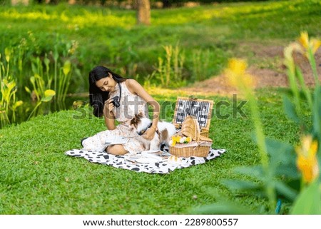 Asian woman using digital camera taking picture her chihuahua dog at dog park. Domestic dog with owner enjoy urban outdoor lifestyle at pets friendly area on summer vacation. Pet Humanization concept.