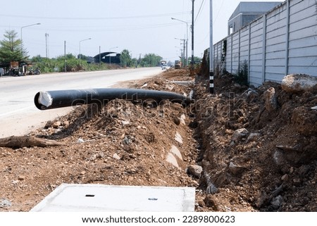 Place black polypropylene plastic drainage pipes underground at the construction site. Buildings and houses, installation of main water pipes on background and underground drainage pipes.
