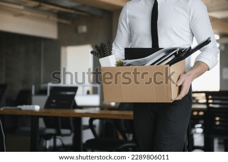 Sad Fired. Let Go Office Worker Packs His Belongings into Cardboard Box and Leaves Office. Workforce Reduction, Downsizing, Reorganization, Restructuring, Outsourcing. Mass Unemployment Market Crisis. Royalty-Free Stock Photo #2289806011