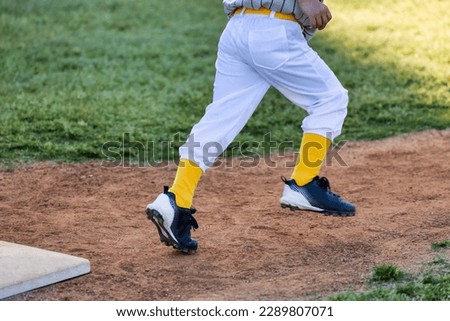 Close-up of Tee ball player running on field with motion blur.
