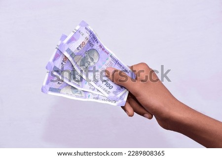 hand holding Indian currency 100 Rupee notes, white background.  Royalty-Free Stock Photo #2289808365