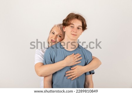 Mothers day, children and family concept - mother hugging her teen boy on white background