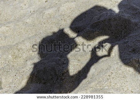 young loving couple shadows making a kiss on tropical sand beach