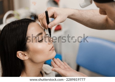 ENT doctor is drawing mark up lines on nose before rhinoplasty surgery. Rhinoplasty markup. Rhinoplasty is reshaping nose surgery for change appearance of the nose and improve breathing Royalty-Free Stock Photo #2289819777