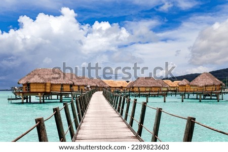 Overwater bungalows stretching and a wooden bridge out across the lagoon in Bora Bora island, Tahiti. Romantic honeymoon destination. Royalty-Free Stock Photo #2289823603