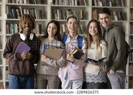 Attractive girls and guys, multi racial schoolmates posing in school library, smile look at camera having good friendly relations, feels satisfied with grades, quality education, new knowledge gaining Royalty-Free Stock Photo #2289826375