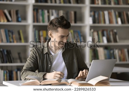 Happy student guy, teenage schoolboy prepare assignment, learn theory, studying in library using laptop. Generation Z gain new knowledge using modern wireless tech and internet resources. Education