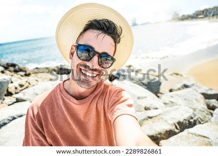 Handsome young man taking selfie with smart mobile phone device outside - Cheerful tourist enjoying summertime at the beach - Life style, traveling and technology concept