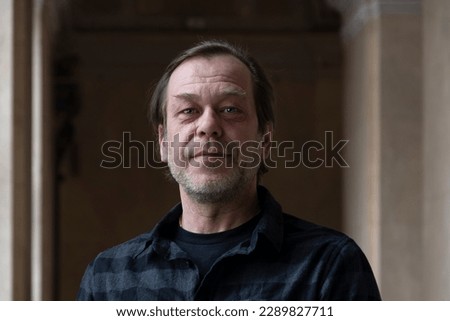 portrait of a man 40-50 years old in a shirt on a neutral blurred background indoors, marble walls. Perhaps he is just a buyer, an actor or a truck driver, a loader or a military pensioner, Royalty-Free Stock Photo #2289827711
