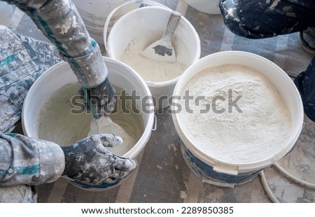Making microcement mortar in medium gray color, making construction mortar Royalty-Free Stock Photo #2289850385