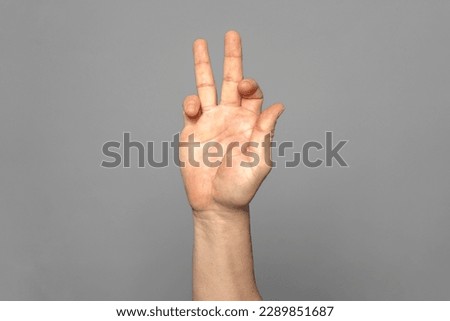 Strong hand of man making a funny gesture of peace and happiness isolated on gray background.