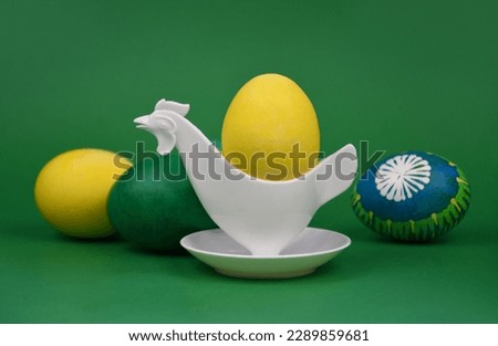Beautiful hand painted unique easter eggs in plastic hen egg cup holder stock images. Easter decoration with colored eggs on a green background stock photo. Retro chicken egg cup still life
