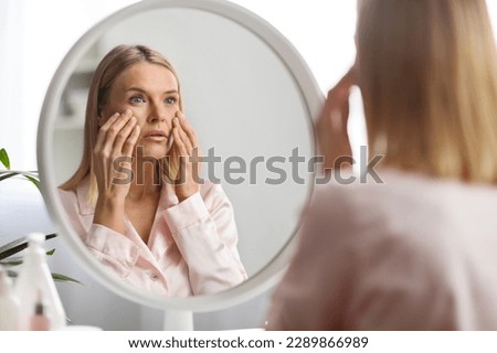 Skin Problems Concept. Upset Middle Aged Woman Looking At Mirror And Touching Face, Confused Mature Lady Noticed Wrinkles And Dark Circles Under Eyes, Unhappy With Skincare Routine, Selective Focus Royalty-Free Stock Photo #2289866989
