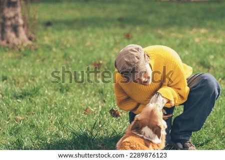 Portrait of a caucasian woman in yellow sweater and checkered cap with corgi dog. Corgi dog kissing his owner High quality photo