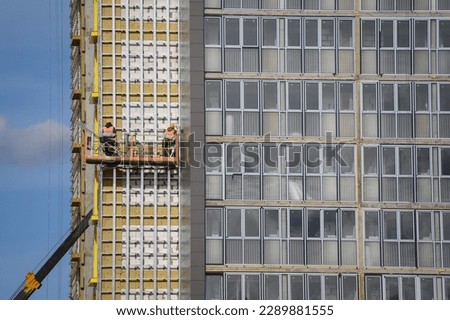Workers sheathe the outer walls of a brick house with insulation. Insulation of the facade of the building. The concept of exterior decoration, moisture protection, sound insulation, energy saving. Royalty-Free Stock Photo #2289881555