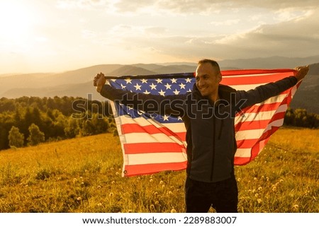 successful silhouette man winner waving American flag on top of the mountain