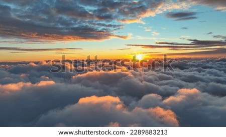 Sun goes into the clouds. Epic sunset in the sky, aerial shot. Flying above the clouds illuminated by the evening sun Royalty-Free Stock Photo #2289883213
