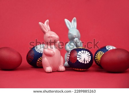 Two cute easter ceramic bunnies figurines and easter eggs stock images. Pink and blue easter bunny spring decoration still life stock photo. Easter decoration with colored eggs on a pink background