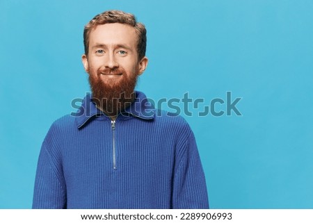 Portrait of man redheaded man with beard in sweater smile and happiness, hand signs and symbols, on blue background. Lifestyle positive, copy place.