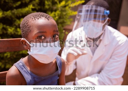 Portrait of a child in a clinic in Africa about to be vaccinated with the doctor beside him Royalty-Free Stock Photo #2289908715