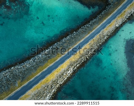Aerial view of road, sea, stones at sunset in Lofoten Islands, Norway. Landscape with beautiful bridge, transparent azure water, rocks. Top down view from drone of highway in summer. Travel. Scenery