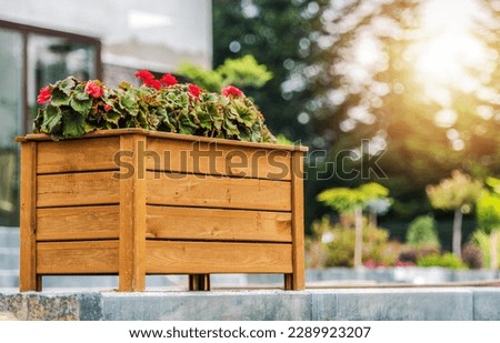 Decorative Wooden Planter Box with Blooming Red Flowers Arranged in the Residential Backyard Garden. Landscaping Design Ideas. Royalty-Free Stock Photo #2289923207