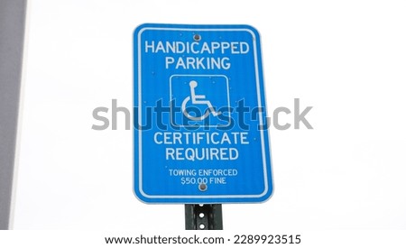 The blue handicap sign on the street is a universal symbol for accessibility and mobility aid for individuals with disabilities, representing equal opportunities and inclusion.